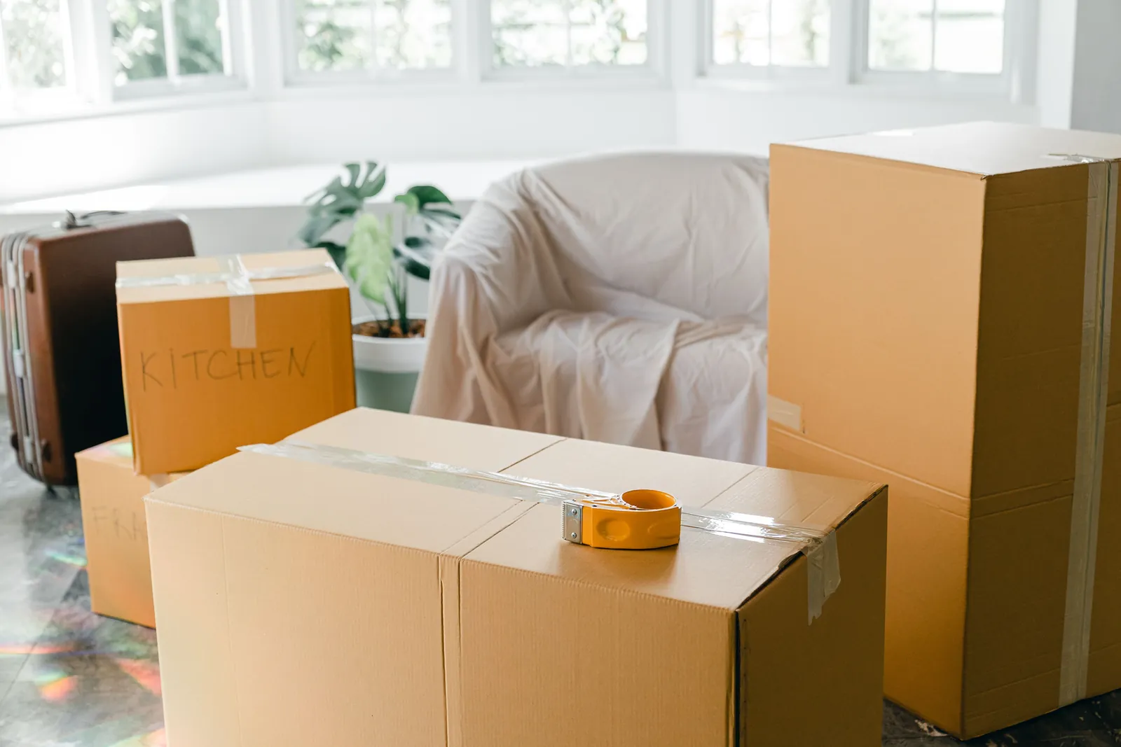 Gepackte Umzugskartons und ein abgedeckter Sessel im Wohnzimmer