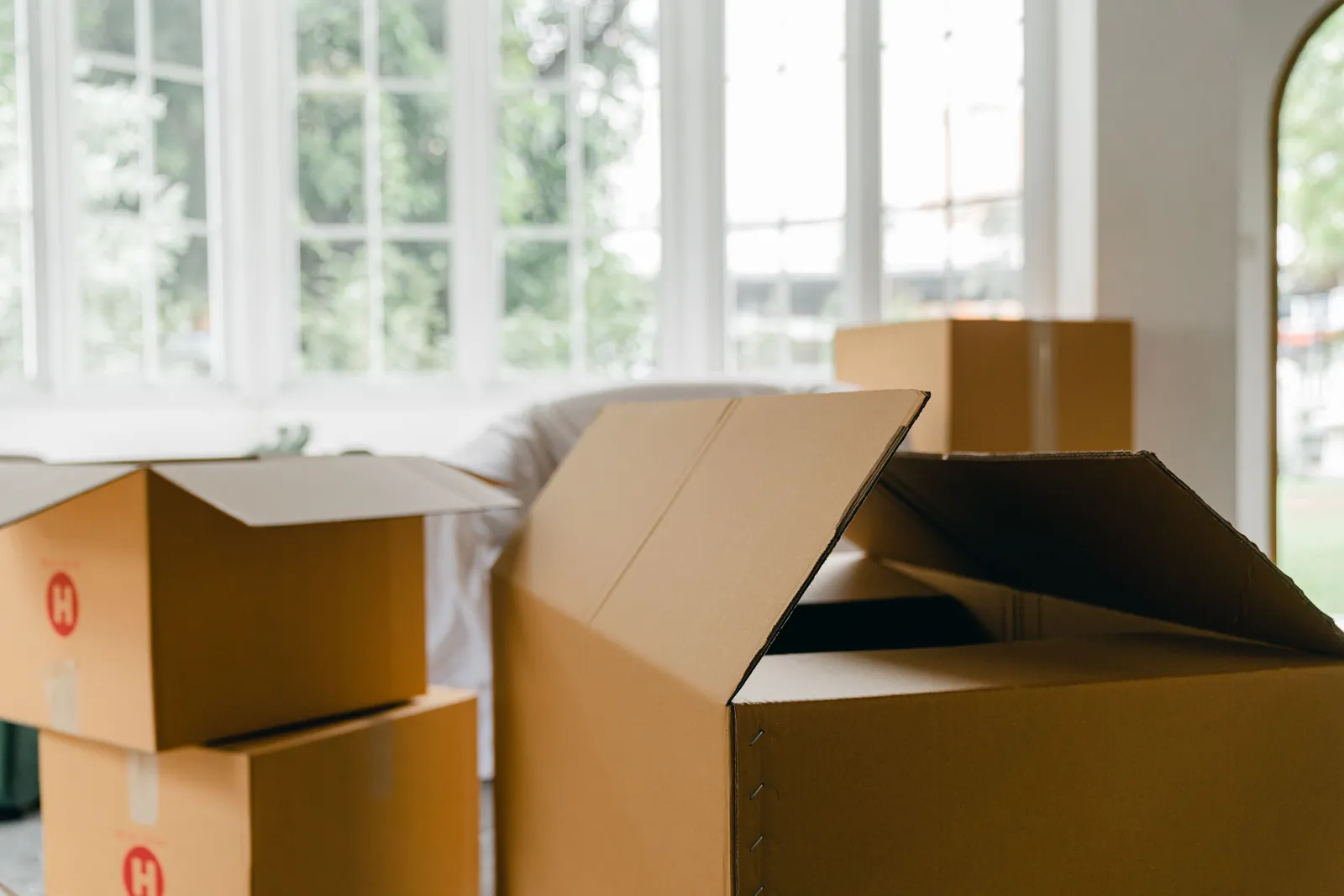Umzugskartons in einer hellen Wohnung vor großen Fenstern